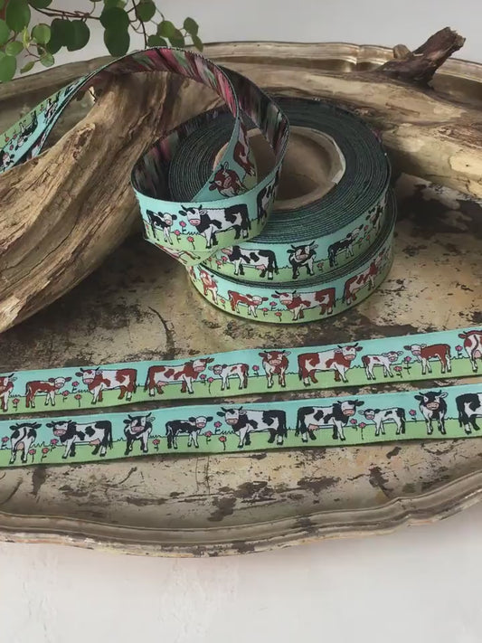 Das Video zoomt and die beiden Webbänder mit schwarz-weißen und braun-weißen Kühen heran und zeigt sie im Detail um Struktur und Materialbeschaffenheit zu erkennen.